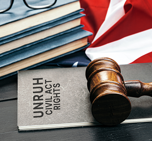 Gavel resting on a book titled Unruh Civil Rights with a backdrop of legal books and an American flag, symbolizing civil rights and legal matters.