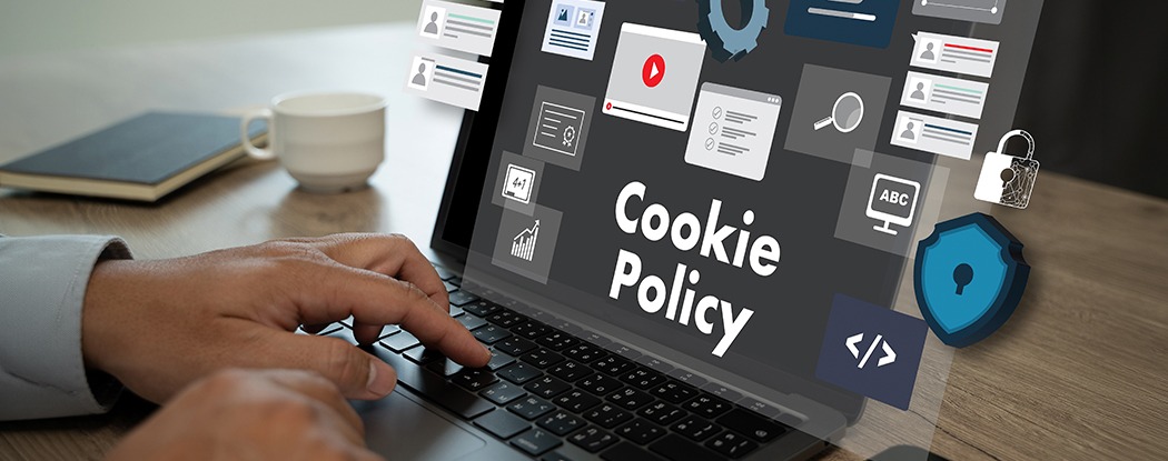 Person using a laptop displaying a Cookie Policy message with privacy, security, and data icons on screen.